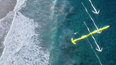  Aerial view of ocean currents, with white arrows indicating the direction of the current, and a yellow arrow indicating the direction one should swim to move out of the current and toward the beach. Credit: Storyblocks 